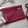 Details des magentaroten Wollschals mit Fransen und Etikett auf strukturiertem Mantel - 180*30cm / Melange Himbeerrosa