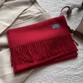 Detail of red wool scarf with fringe and blue woven label on beige fabric - 180*30cm / New Year Red
