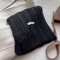 Detail of 100% wool label on black cable knit scarf with soft texture and premium weave - Black