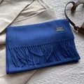 Detailed close-up of dark blue 100% wool scarf featuring fringe trim and brand woven label - 180*30cm / Azure Blue