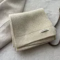Detail of beige waffle knit scarf with textured wool fabric and minimalist brand label - Off White