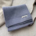 Close-up of light purple knitted scarf texture with a white rectangular design label - Lavender