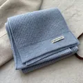 Nahaufnahme der blauen Waffelstrick-Wollschal-Struktur mit einem weißen Zieretikett - Hellblau
