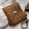 Detailed macro view of 100% wool caramel brown cable knit scarf showing soft texture - Orange
