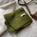 Detalle de bufanda de lana pura con etiqueta 100% lana y textura tejida de alta calidad - Verde bosque