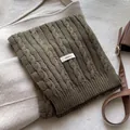 Detail of dark green cable knit wool scarf featuring a 100% wool material label - Coffee