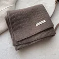 Detailansicht des dicken braunen Rippstrickschals aus Wolle mit weißem Textiletikett - Kaffeebraun