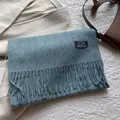 Detail of blue-grey wool scarf featuring soft cashmere texture and woven quote label - 180*30cm / Astral Blue