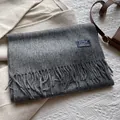 Detail shot of a dark grey wool scarf with fine tassels and a minimalist brand label - 180*30cm / Marl Grey