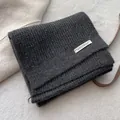 Close-up of dark grey waffle knit texture and fabric label on thick winter scarf - Gray