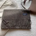 Close-up of a dark brown wool scarf with tassel details and a blue woven label - 180*30cm / Mocha Coffee
