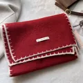Dettaglio di sciarpa in maglia rossa con cuciture bianche ed etichetta in tessuto - Rosso
