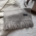 Close-up of luxury grey wool scarf with long tassels and minimalist brand label - 180*30cm / Milky Apricot