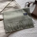 Detail of sage green wool scarf with fringe edges and rectangular woven brand tag - 180*30cm / Bean Green