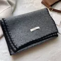 Dettaglio ravvicinato della sciarpa in maglia grigio scuro con bordo nero e etichetta - Grigio
