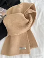 Dicker kamelfarbener Strickschal mit vertikalem Rippenmuster und weißem Etikett-Detail - Camel