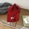 Winter red knitted wool balaclava with buttons and drawstring on a wooden table - Red