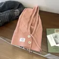 Details der Strickstruktur des rosa Woll-Balaclava mit Zopfmuster und weißen Knöpfen - Rosa