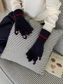 Détail de gants tricotés montrant les ouvertures tactiles et rayures rouges au poignet - Bleu marine