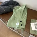 Detailansicht der kabelgestrickten grünen Sturmhaube mit Zierknöpfen und gewebtem Aufnäher - Grün