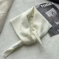 Close-up of cream wool knit triangle scarf with a Modeng Mi brand label on fabric - 100x30cm / Ivory