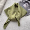 Détail d'un foulard triangulaire en tricot vert avec étiquette sur fond gris texturé - 100x30cm / Vert