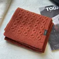 Detailed macro view of 100% pure wool knitted scarf texture with fabric composition label - Orange