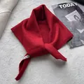 Detail shot of a red knitted triangle scarf with a soft wool texture and brand label - 100x30cm / Red