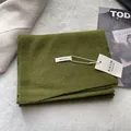 Close-up of 100% pure wool label on folded grass green knitted scarf with soft texture - Olive Green
