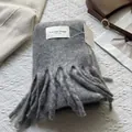 Detail of grey wool scarf featuring long tassels, a white woven label, and paper gift tags - 180*30cm / Elegant Paris Gray