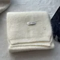 Detail of soft cream knitted wool scarf with ERET WOOL label and silver B charm pendant - Off White