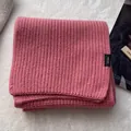 Close-up of pink 100% wool scarf featuring thick rib knit texture and material tag - Pink