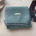 Detailed view of teal knit wool scarf featuring brand label and silver metal B logo charm - Lake Blue