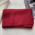 Dettaglio di una sciarpa rossa in 100% lana con trama a trecce ed etichetta di lavaggio - Rosso
