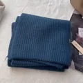 Detail shot of navy blue 100% wool knitted scarf showing texture and washing label - Navy Blue