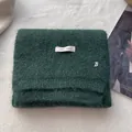 Detailed macro view of dark green knit wool scarf with ERET WOOL label and metal B logo - Green