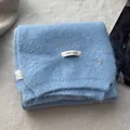 Detail of light blue wool knit scarf with brand label and golden B metal ornament - Sea Salt Blue