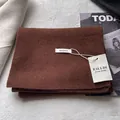Detail of dark brown 100% Australian wool scarf with handmade label and soft texture - Coffee