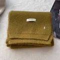 Detail of wool knit scarf with brand label and silver metal B charm on mustard fabric - Mustard Green