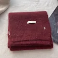 Close-up of wine red wool knit scarf with soft brushed texture and metal B pendant - Ancorra Red