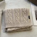 Close-up of beige wool scarf showing thick cable knit texture and 100% wool label - Off White