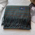 Detail eines blauen Hahnentritt-Schals mit dicken Quasten und Premium-Markenlabel - Dunkelgrün Camel
