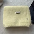 Close-up of soft yellow wool knit scarf featuring a silver metal B pendant detail - Light Yellow