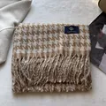 Close-up of thick houndstooth scarf with fringe tassels and woven brand label - Camel Beige