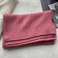 Detail of pink wool scarf with chunky cable knit texture and 100% wool material tag - Pink