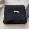 Detail of black wool knit scarf featuring a white brand tag and silver metal B ornament - Elegant Black