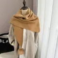 Détail d'une écharpe en maille moutarde épaisse avec un pompon en fausse fourrure - Chameau