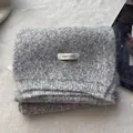 Detailed texture of grey wool knit scarf featuring a silver metal letter B logo - Gray