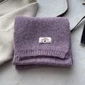 Close-up of purple wool blend scarf showing textured knit, rib edge and brand label - Taro Purple