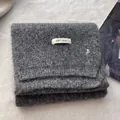 Close-up of dark grey wool knit scarf with brand label and silver metal B pendant - Dark Gray